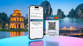 A promotional image for a 15-day Vietnam travel eSIM plan. It shows an iPhone displaying active mobile data with the 'Vietnam Travel eSIM' plan, providing 5GB of high-speed data daily, plus unlimited local calls and texts, for 15 days. The screen indicates compatibility with Viettel, Vinaphone, and Mobifone networks. Next to it is an eSIM QR code card. The background is a combination of modern Ho Chi Minh City at night and historical Turtle Tower.